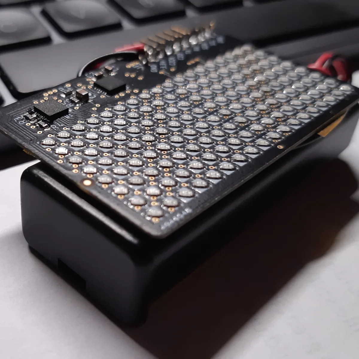 Close-up of a small dot matrix LED display board mounted on a black battery holder